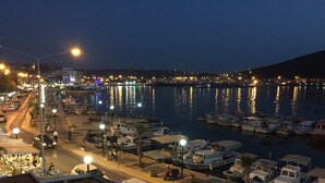 A marina at night with boats docked, street lights, and a view of the water reflecting lights. - Ufuk Hotel (Çeşme)