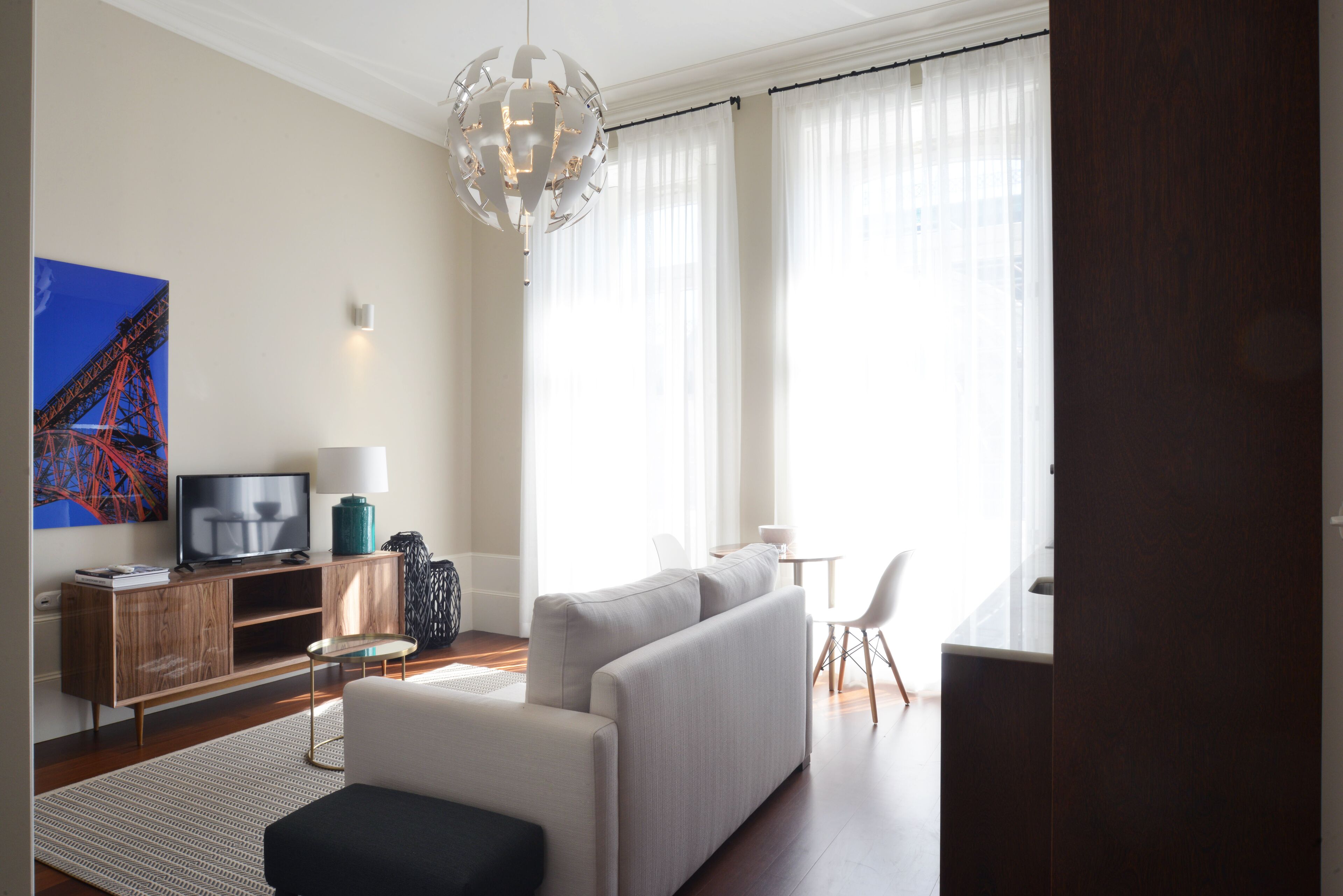 Ein modernes Wohnzimmer mit Sofa, Fernseher, Lampe und Essbereich.