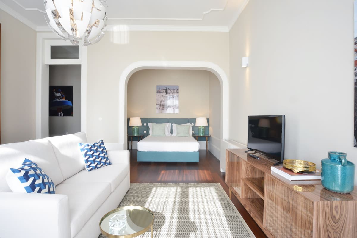 A modern bedroom with a bed, a TV, a sofa, and a console table.