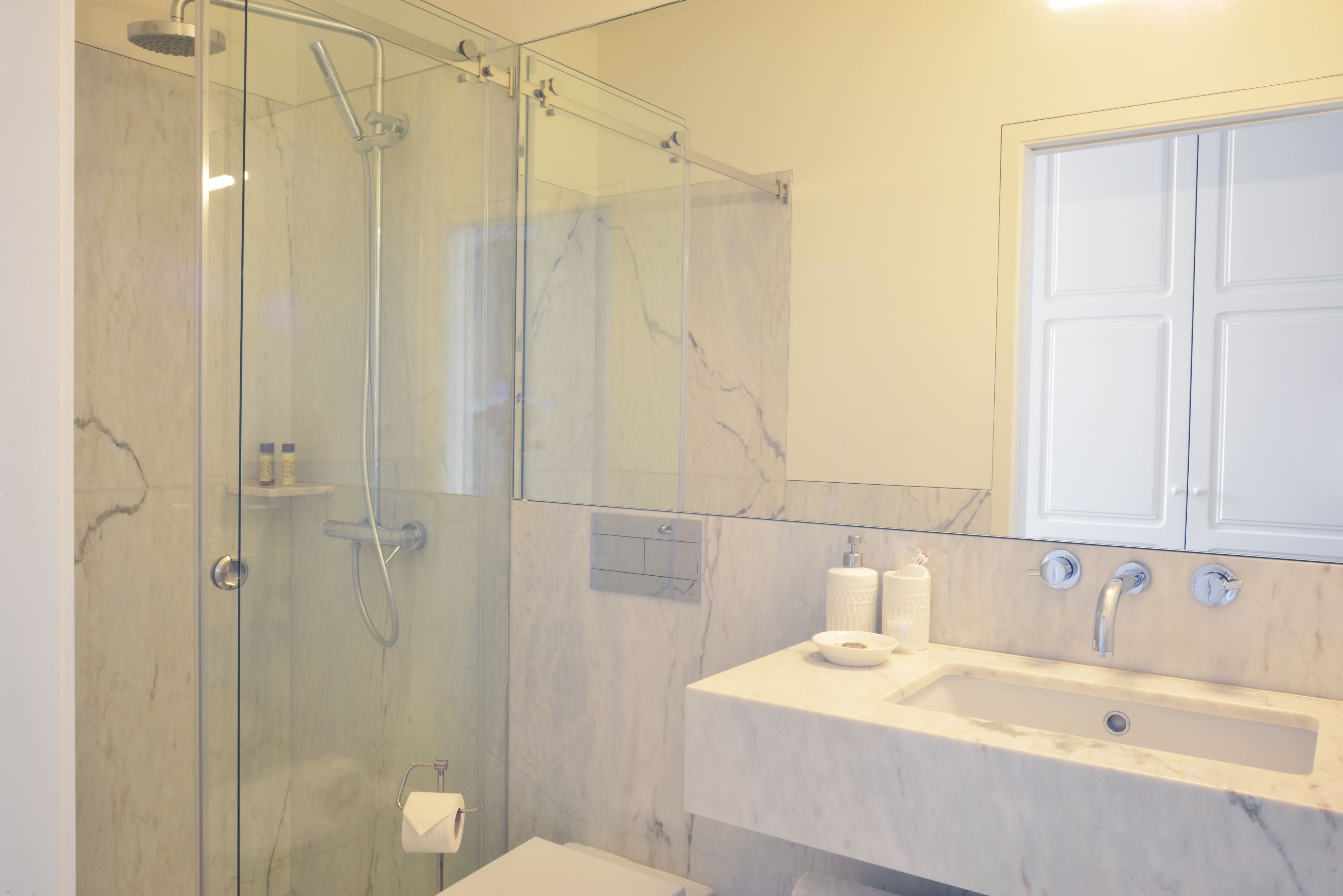 A modern bathroom with a glass-enclosed shower, a marble sink, and a white vanity.