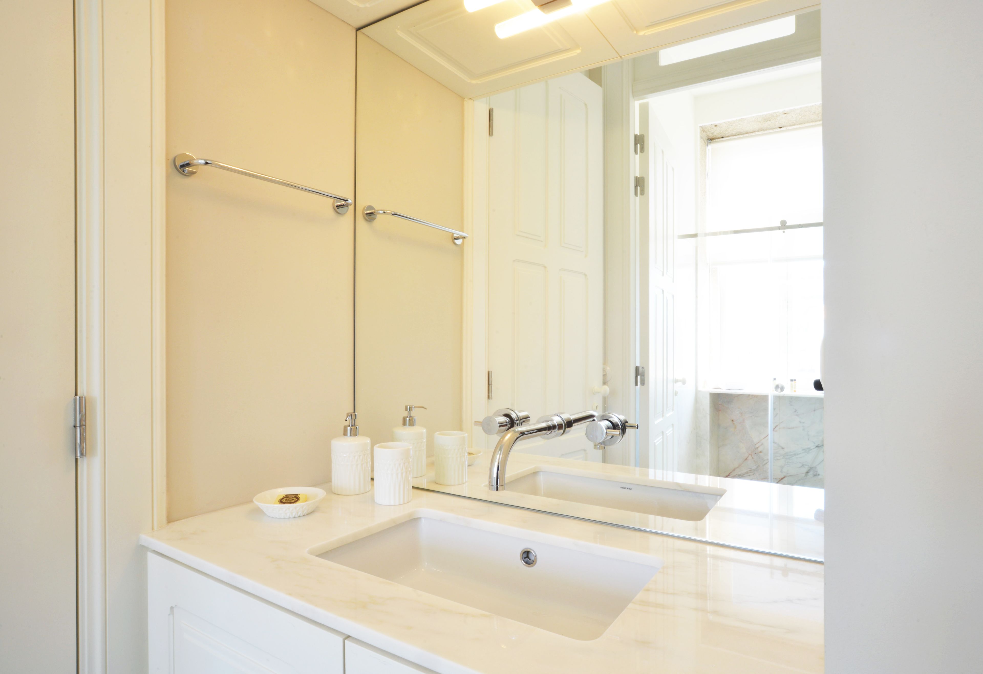 A bathroom with a large mirror, a sink, and a towel rack.