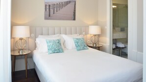 A neatly made bed with two pillows, a headboard, and two bedside tables with lamps. - YOUROPO - Market (Porto)