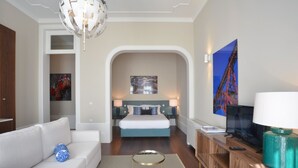 A modern hotel room with a large bed, a sofa, a television, and a desk. - YOUROPO - Market (Porto)