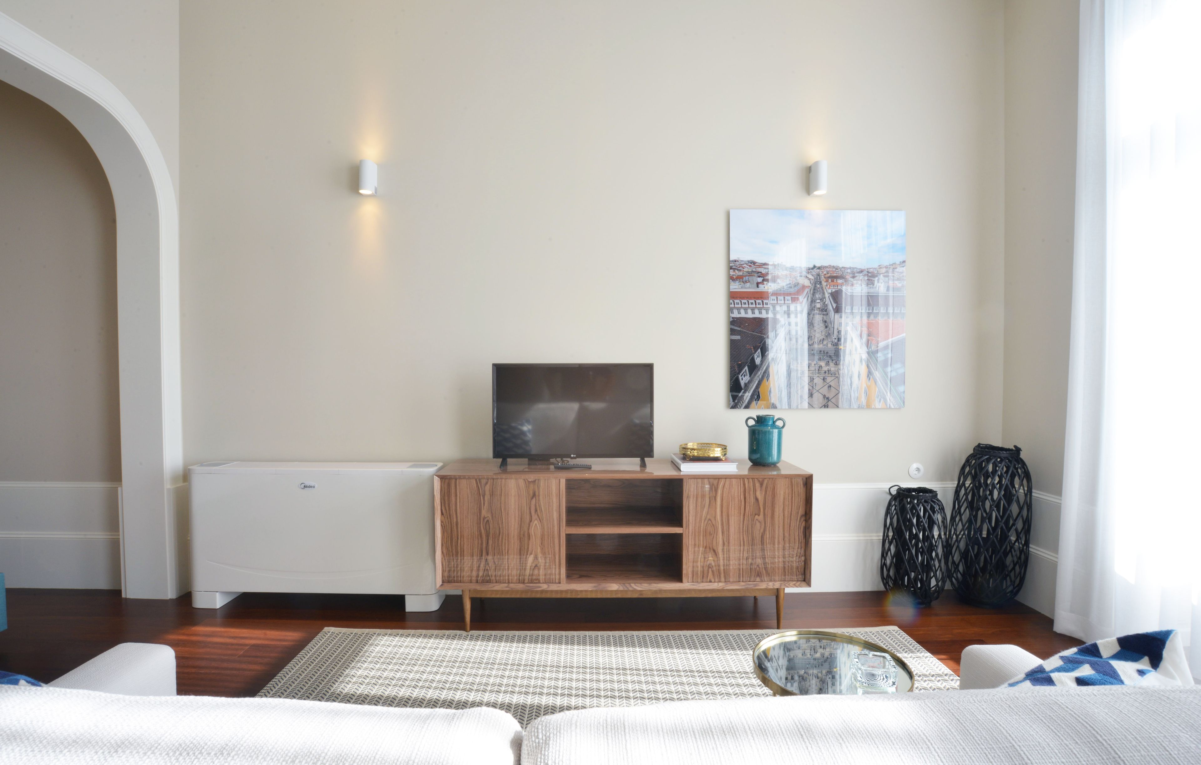 A modern living room with a wooden cabinet, a flat-screen TV, and a painting on the wall.