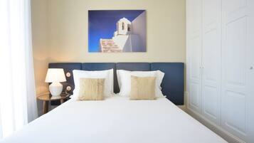 Una habitación de hotel con una cama, dos mesitas de noche, una lámpara y un cuadro colgado en la pared de un edificio.