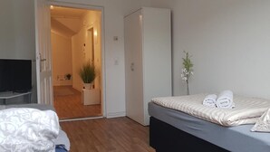 Une chambre d’hôtel avec un lit, une télévision, une armoire et une plante en pot.