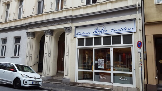 Un bâtiment sur lequel on peut lire l’inscription « Bäckerei Roder Konditorei » et devant lequel est garée une voiture blanche.
