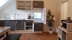 Une cuisine compacte équipée d’un four encastré, d’un four à micro-ondes et d’un réfrigérateur.