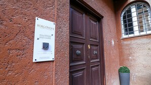 Eine braune Doppeltür mit einer Schilder, auf der 'BORGONOVE GUESTHOUSE' und 'Zimmer 11-12' stehen.