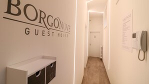Ein Flur mit einem Schild, auf dem ‘BORCONOVE GUEST HOUSE’ steht, und einem Telefon an der Wand.
