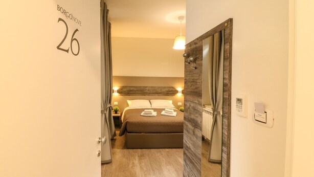 Ein Hotelzimmer mit Bett, Nachttisch, Lampe und Spiegel.