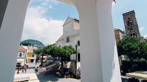 A courtyard with a white building, a bell tower, and a mountain in the background. - Ravello In (Ravello)
