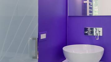 A modern bathroom with a purple wall, a white sink, and a mirror.