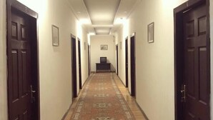 Um corredor comprido e estreito com portas de madeira em ambos os lados, um tapete estampado e iluminação embutida.
