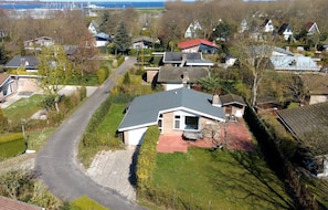 An aerial view of a residential area with houses, a winding road, and a body of water in the background.