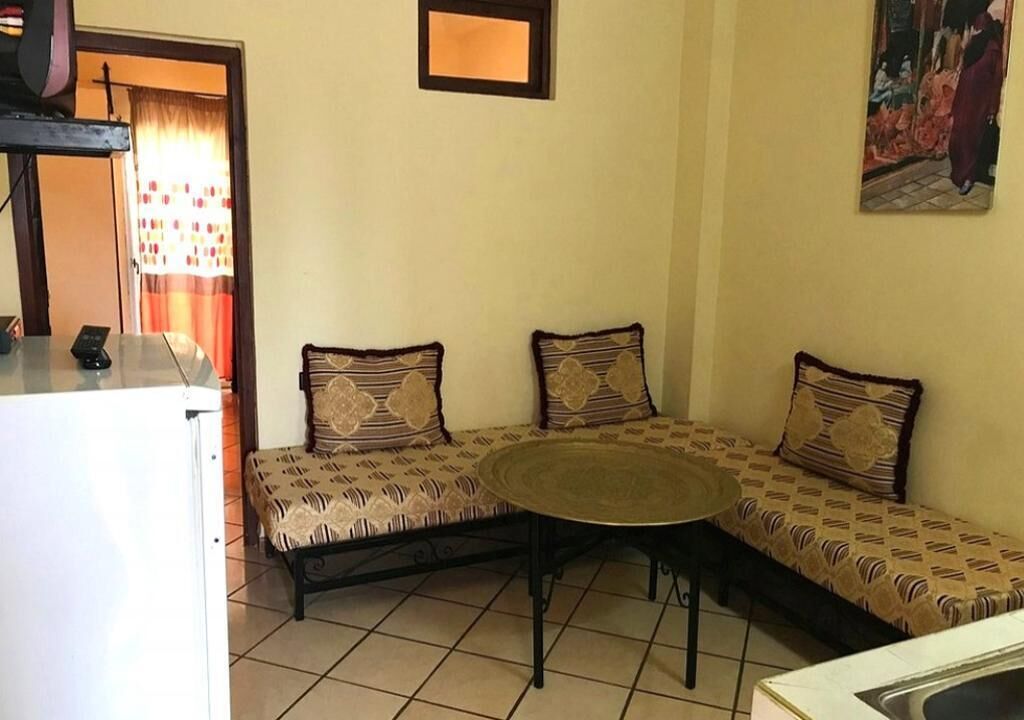 Un coin salon avec des coussins à motifs, une table ronde et un sol carrelé.