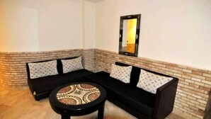 Sala de estar en esquina con un sofá modular negro, una mesa redonda y una pared de ladrillo decorativa.