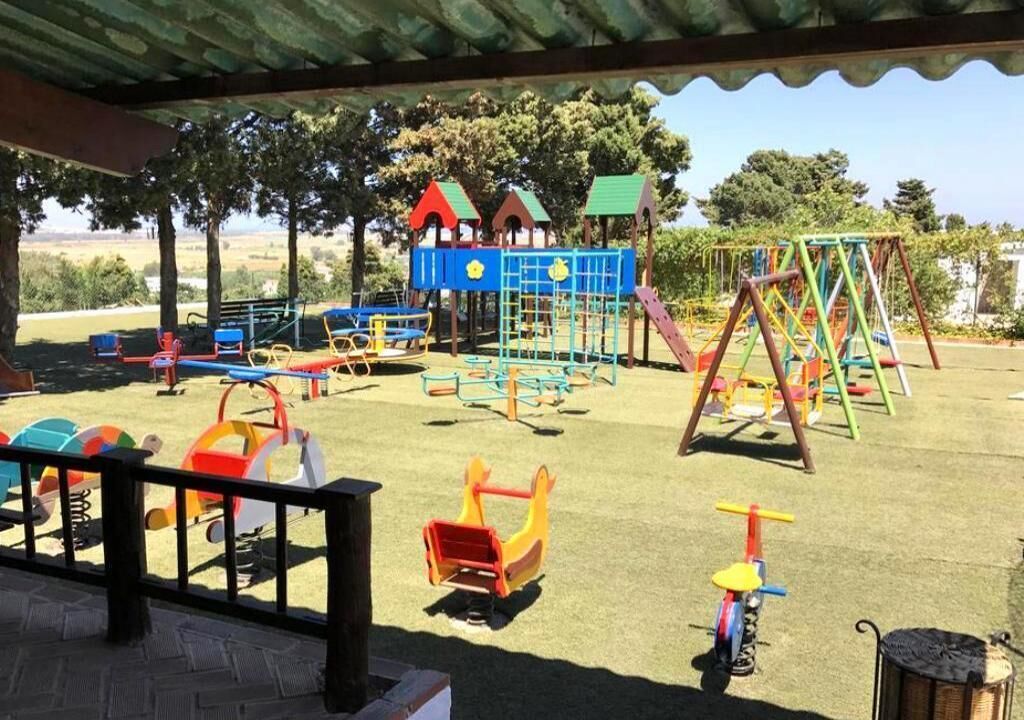 A playground with various play structures including slides, swings, and climbing frames.