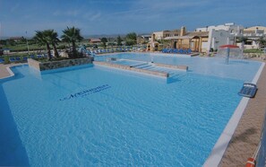 Una piscina al aire libre, sombrillas, tumbonas