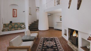 A spacious living area with a fireplace, a staircase, and a seating area with a patterned sofa. - Villaggio Turistico Le Meridiane (Montenero di Bisaccia)