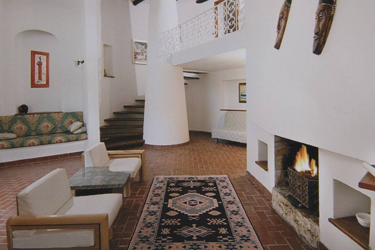 Un vaste espace de vie doté d’une cheminée, d’un escalier et d’un coin salon avec un canapé à motifs.
