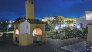 A courtyard with two outdoor ovens, a building with a tower, and a paved walkway. - Villaggio Turistico Le Meridiane (Montenero di Bisaccia)