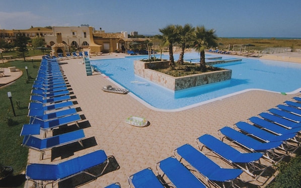 Zona de piscina con sillas reclinables azules y una piscina pequeña.
