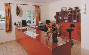 Un mostrador de recepción con un florero, una computadora y una estantería.