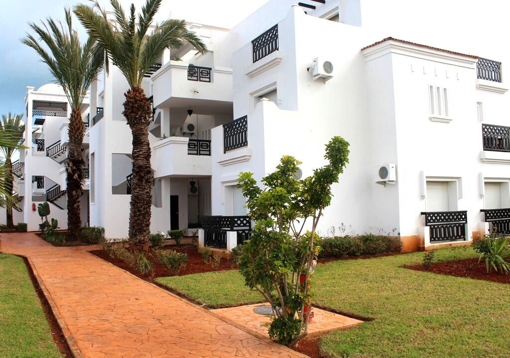 A white building with balconies and palm trees.