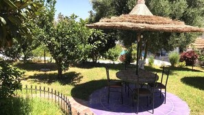 A gazebo with a thatched roof, surrounded by a circular seating area with chairs.
