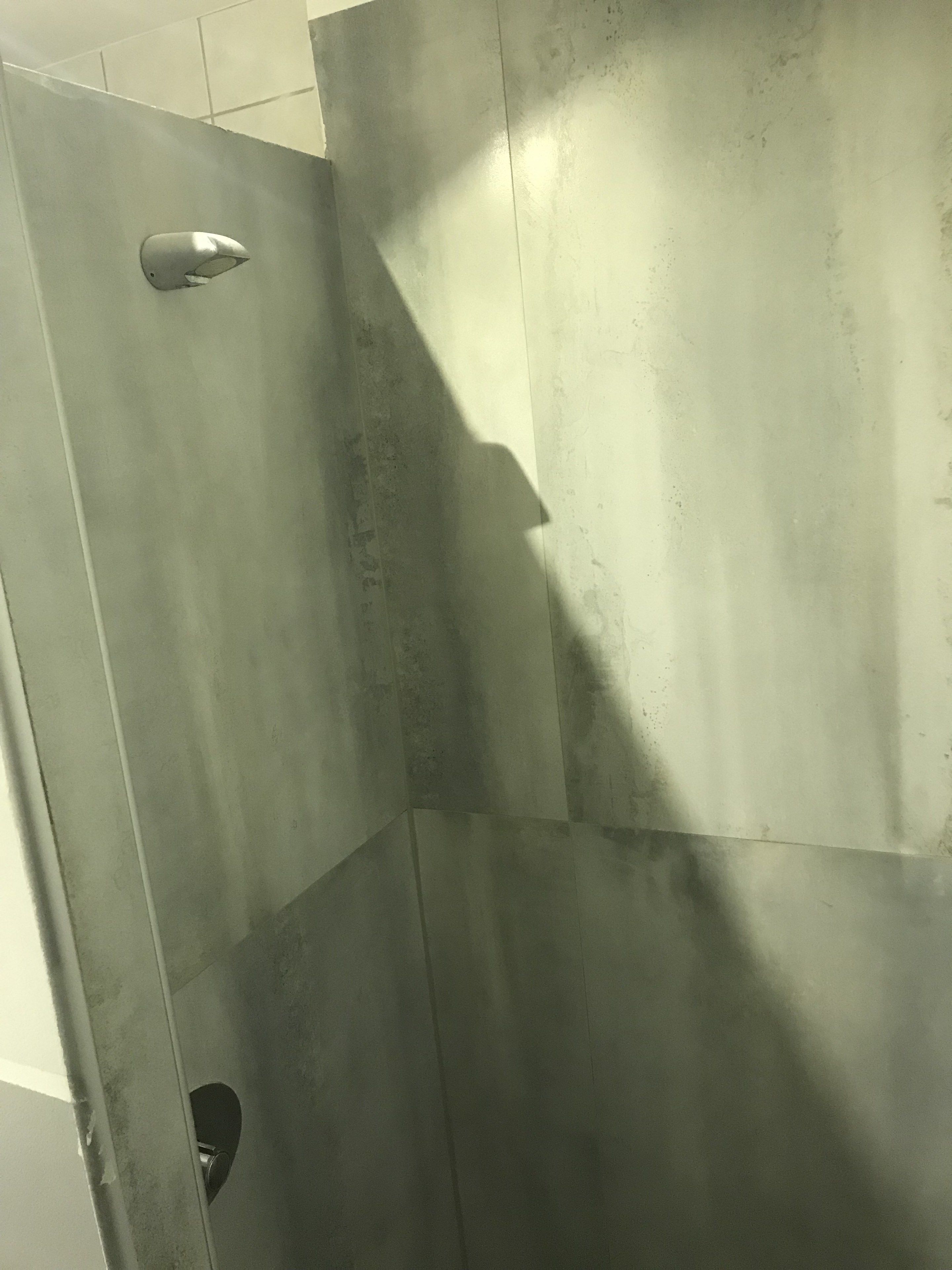 Un área de ducha con puerta metálica y desagüe a la vista.