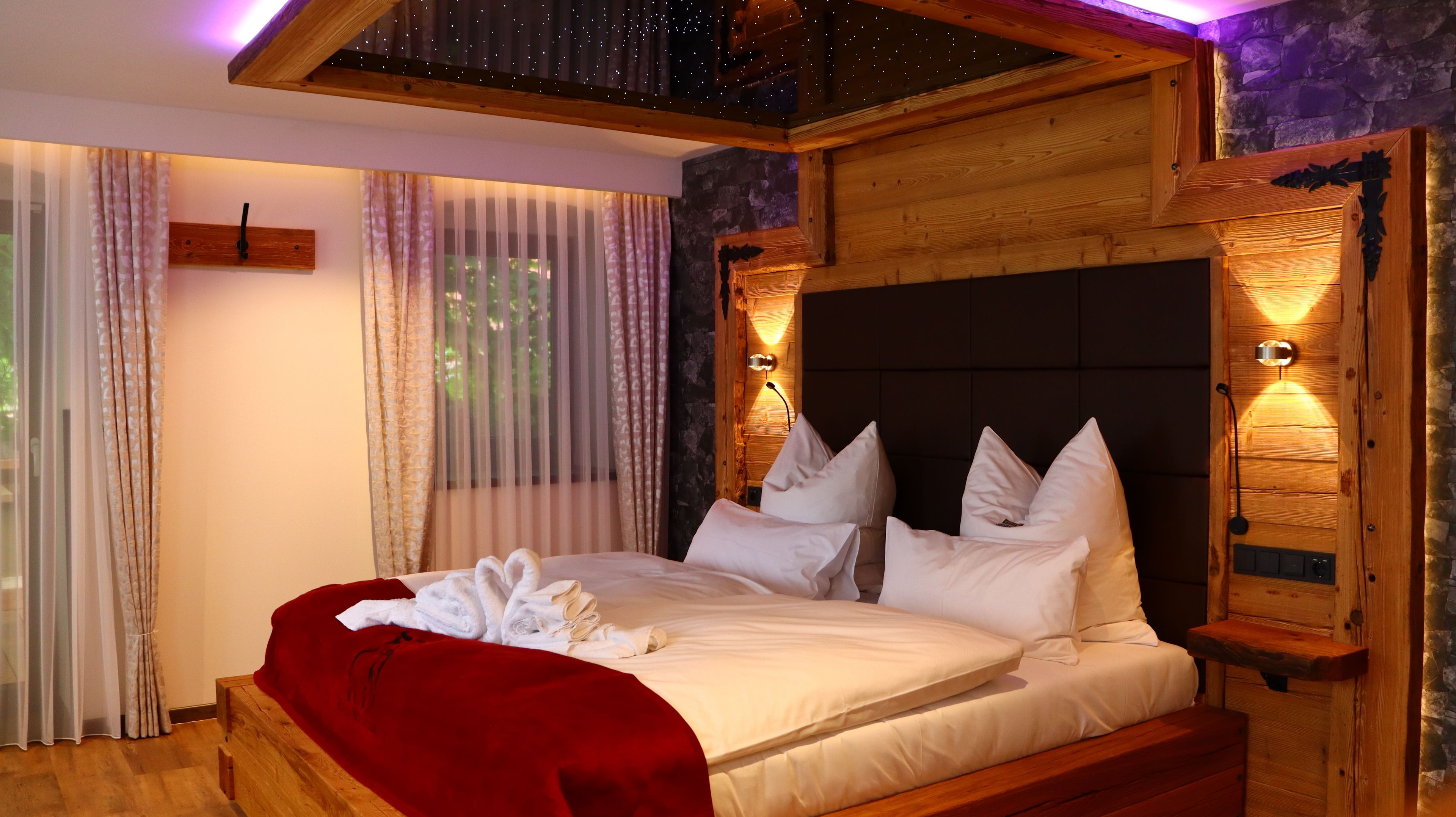 Camera da letto con struttura in legno, letto, tende e illuminazione a parete.