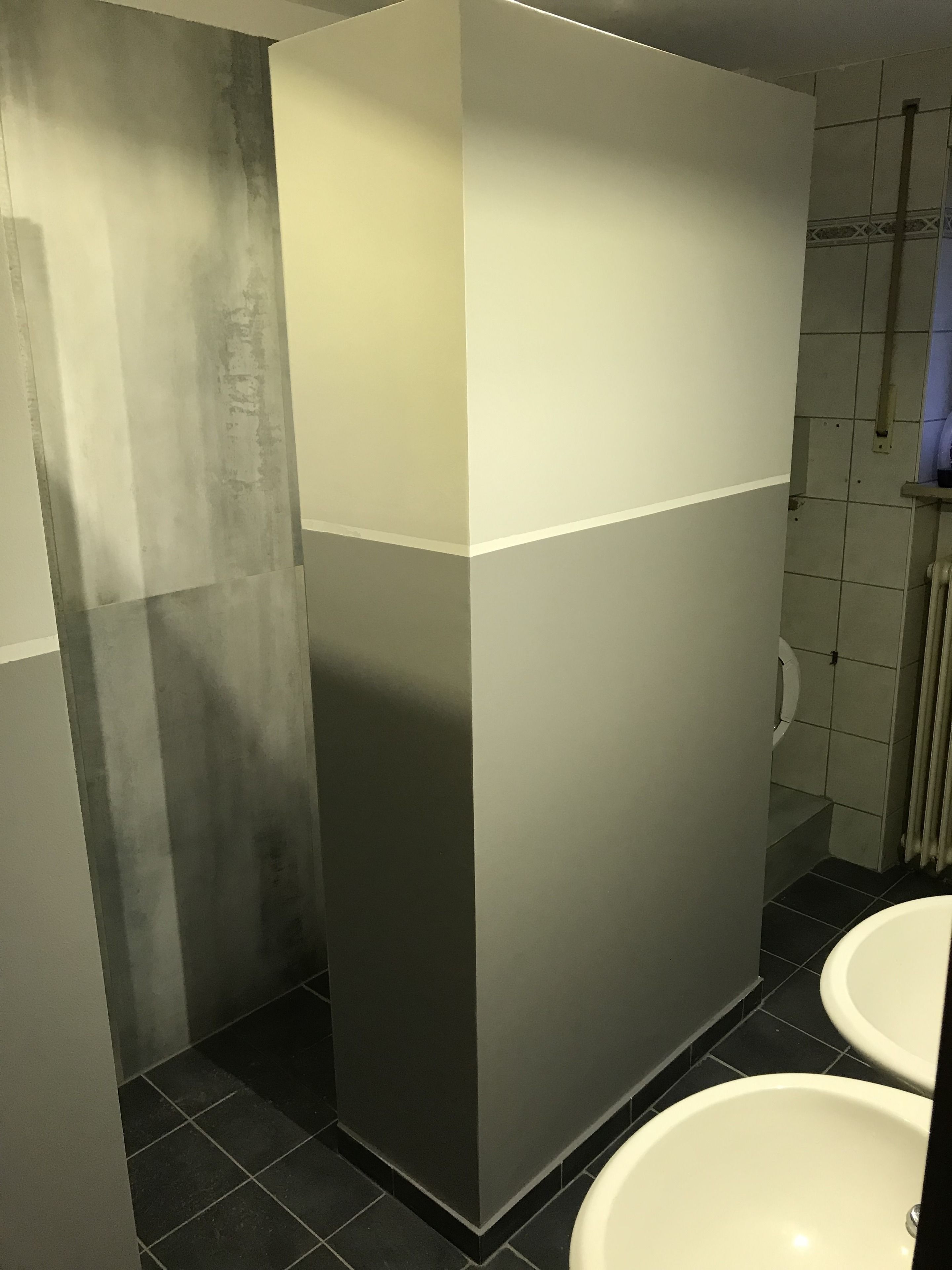 Un baño con diseño moderno, que incluye un espejo grande, un inodoro y un lavamanos.