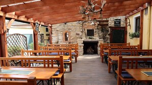 Un restaurant avec des tables et des bancs en bois, des murs en pierre et une cheminée.
