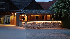Un bâtiment rustique avec un mur en pierre et des poutres en bois, doté d’un escalier en pierre menant à une porte en bois.