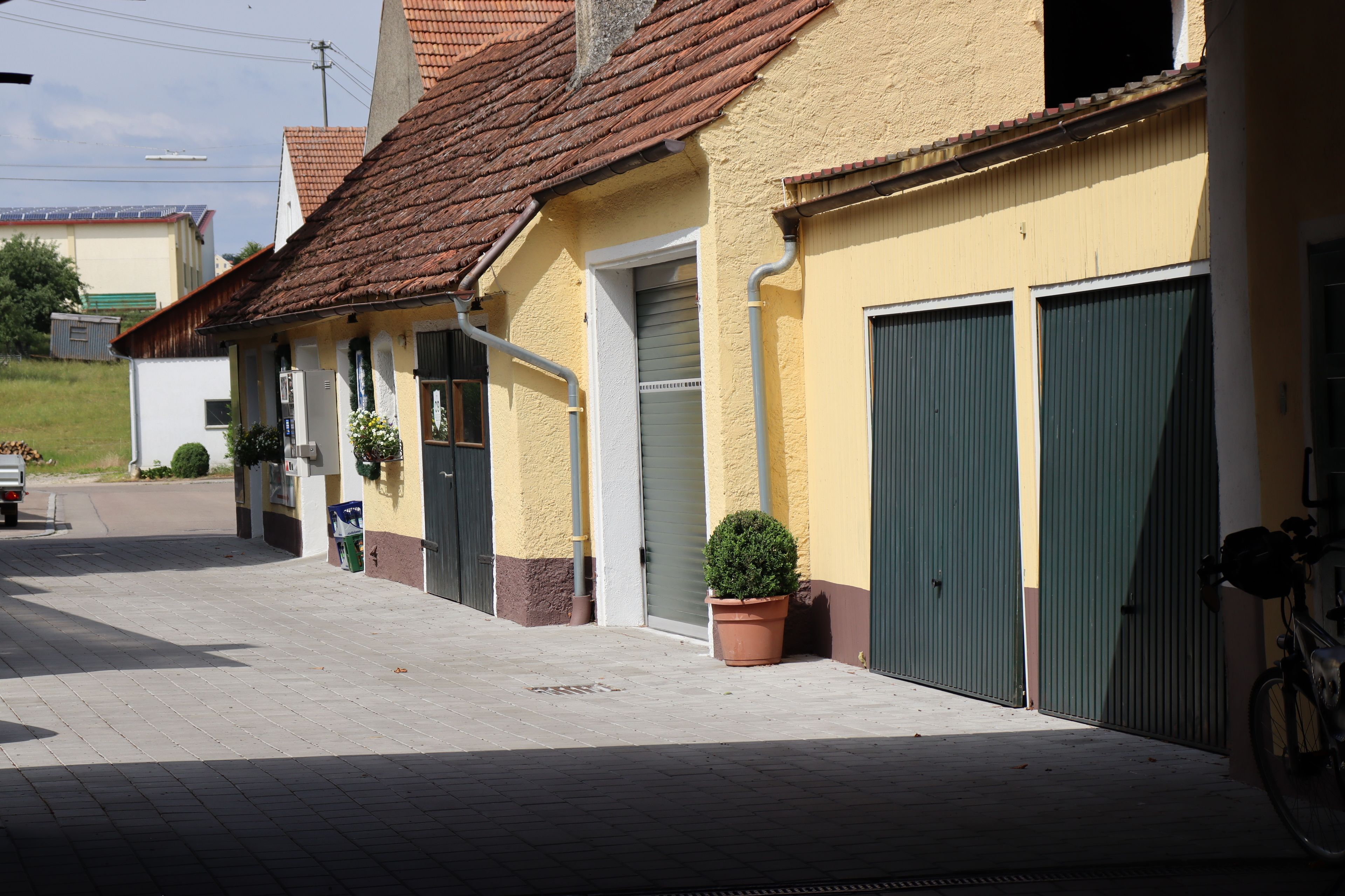 A building with a yellow facade, a tiled roof, and a green door.