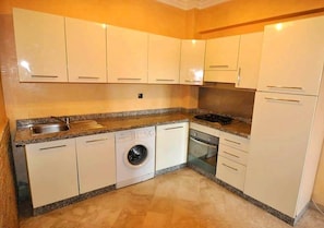 A compact kitchen with white cabinets, a built-in washing machine, and a dishwasher.