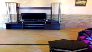 Un soggiorno con televisione a schermo piatto, un tavolino da caffè in vetro e un piccolo tavolino laterale.