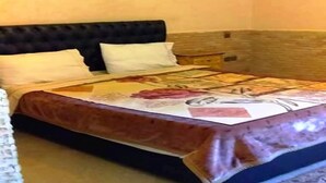 Un letto con una coperta a motivi floreali, una testata scura e un comodino con una lampada.