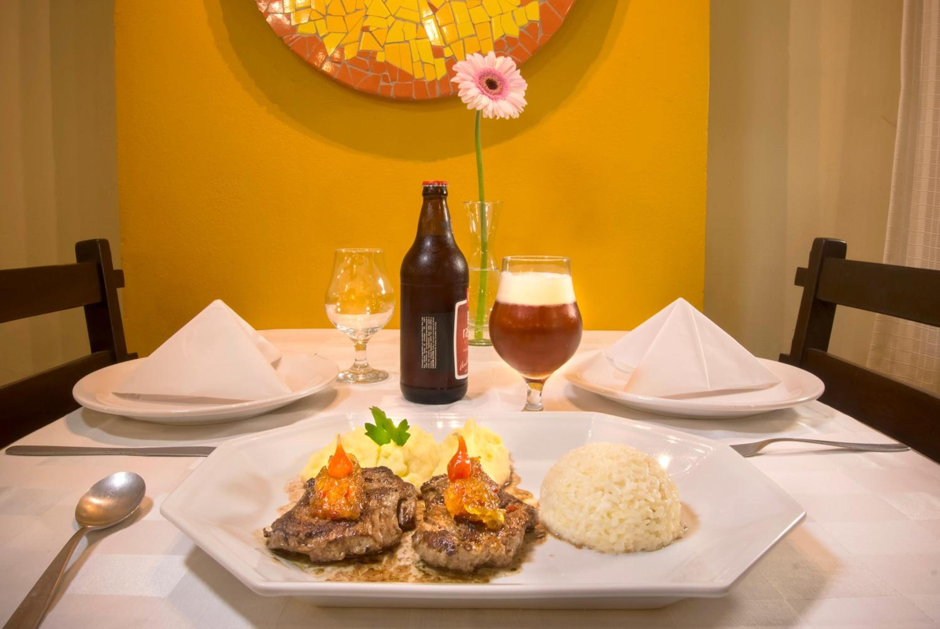 Uma mesa de jantar com um prato de comida, uma garrafa e um copo de cerveja.
