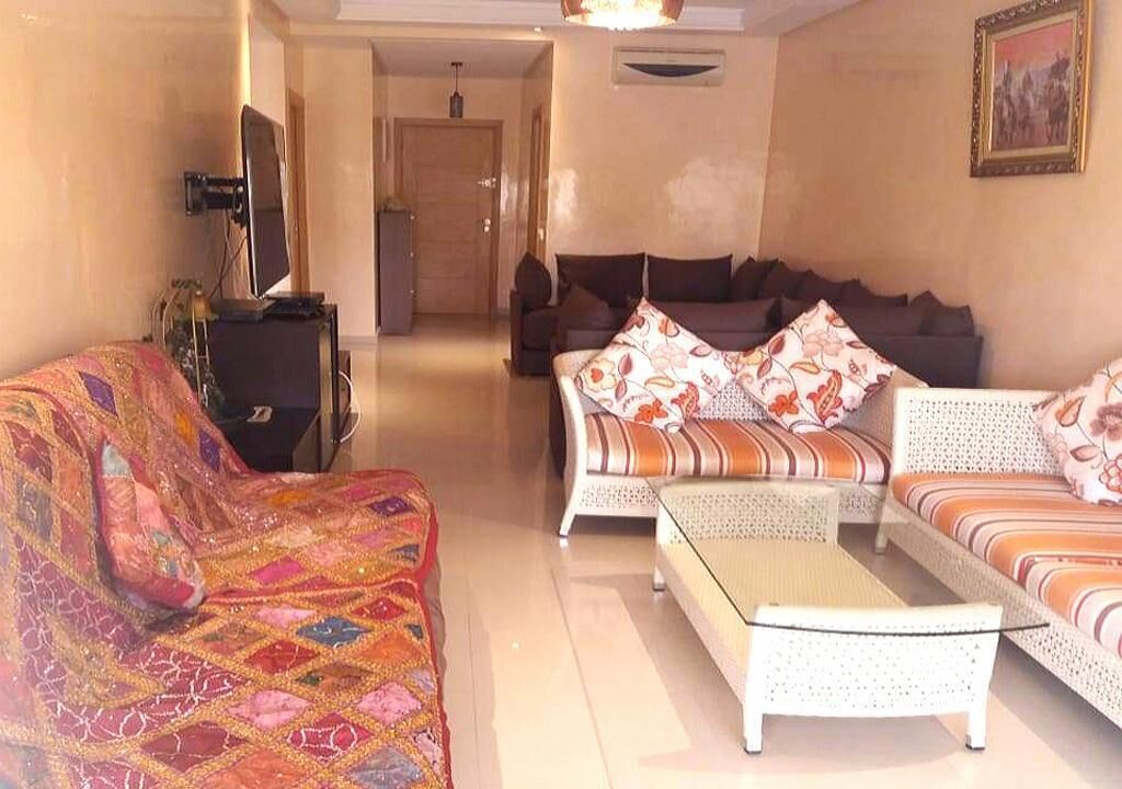 A living room with a patterned sofa, a white sofa with floral cushions, and a coffee table.