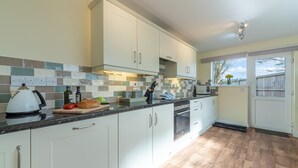 Eine moderne Küche mit weißen Schränken, einer gefliesten Spritzschutzwand und Holzboden.