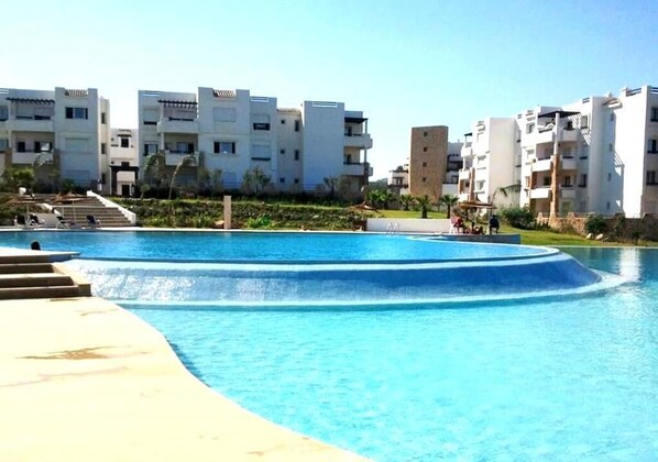 Una piscina amb escales d'accés, envoltada d'edificis d'apartaments moderns.