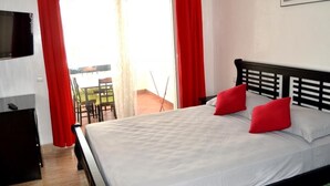 A hotel room with a bed, red curtains, a TV, and a balcony with a table and chairs. - Residence Playa del Pacha Mdiq 3407 (Mdiq)