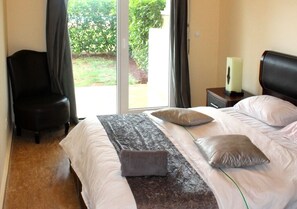 Relax in this serene space with a large bed, a comfortable chair, and a view of the garden through a sliding door.