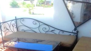 Ein Zimmer mit einem Metallbettgestell, einer Bank und einer blauen Kiste auf dem Boden.