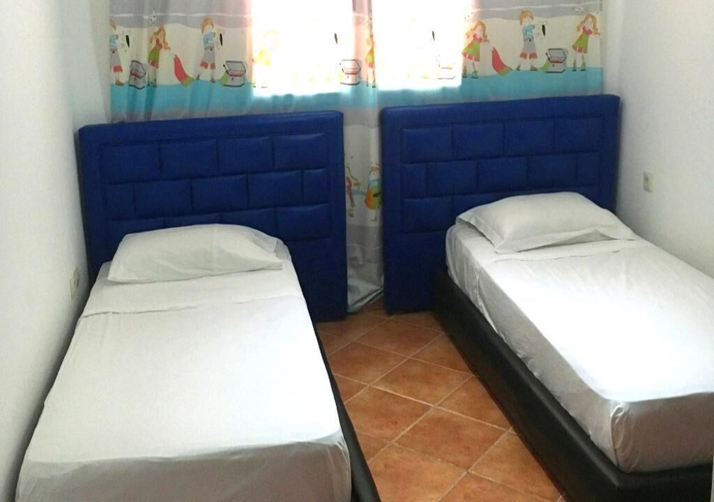 Ein Zimmer mit zwei Einzelbetten, jeweils mit blauer Kopfteil und weißer Bettwäsche.