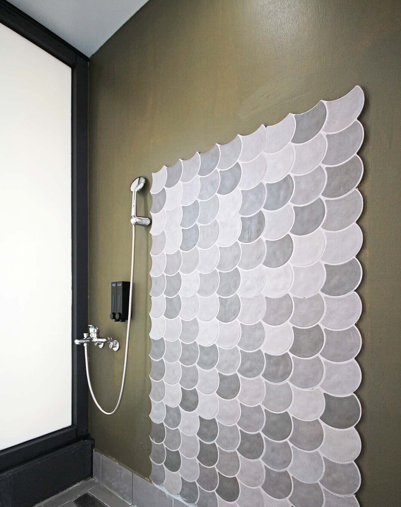 A bathroom with a shower area featuring a unique tiled wall design.