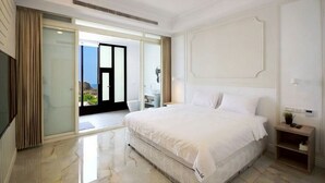 A spacious bedroom with a large bed, a sliding glass door leading to a balcony, and a television on the left. - House16 (Lyudao)