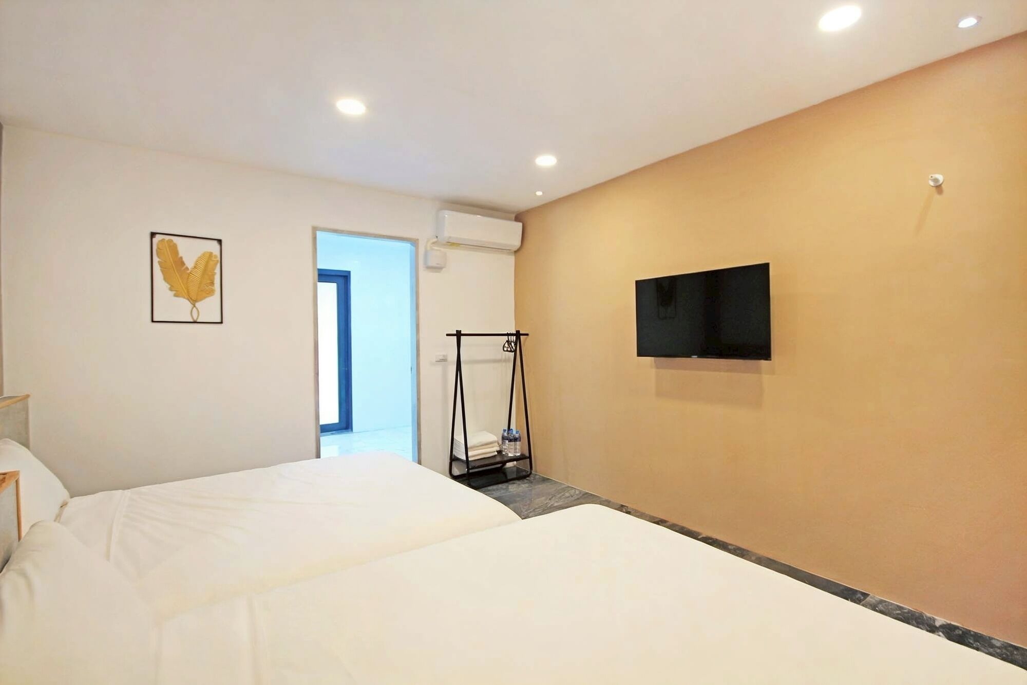 A hotel room with a bed, a television mounted on the wall, and a door leading to another room.